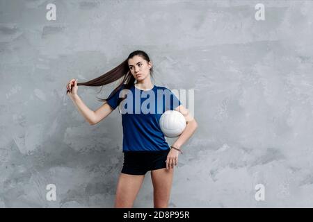 Volleyball girl hold white ball on grey background. Player doing sport workout at home Sport and recreation concept. Vintage color filter. Stock Photo