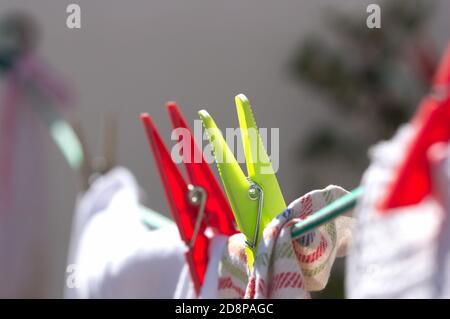 Close-up of clothespins that hold home clothes hanging on a rope to dry in the sun Stock Photo