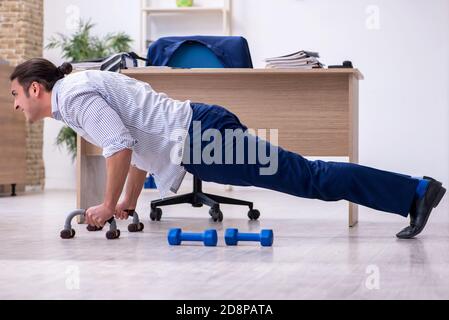 Handsome male employee doing exercises in the office Stock Photo