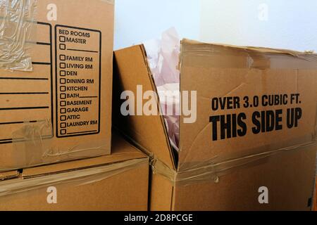 Moving cardboard boxes with printed list of items for each room: bed room, family, den, dining, kitchen, bath, basement, garage, attic, laundry room. Stock Photo