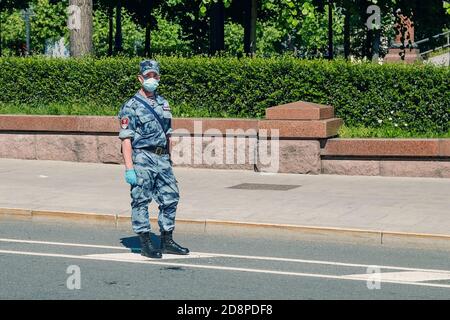 Young soldier of Russia Guard wearing summer camouflage, protective mask and gloves working on the street  Stock Photo