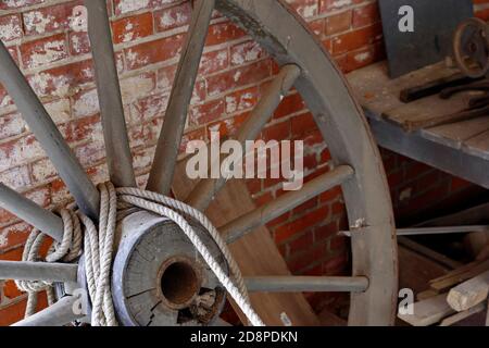 Decaying wagon wheel against a red brick wall. Fort Delaware, Pea Patch Island, DE. Stock Photo