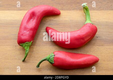 Overhead view of whole red peppers on a cutting board. Stock Photo