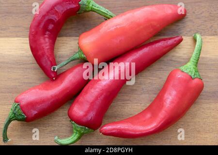 Overhead view of whole red peppers on a cutting board. Stock Photo