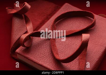 Curled red leather strap on top of a red leather bound diary Stock Photo