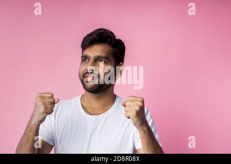 People, success, win, good news and celebration. Happy successful young indian male raising hands, clenching fists in triumph, celebrating victory, we Stock Photo