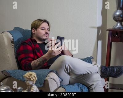 Caucasian man with tattoos looking at his smartphone Stock Photo