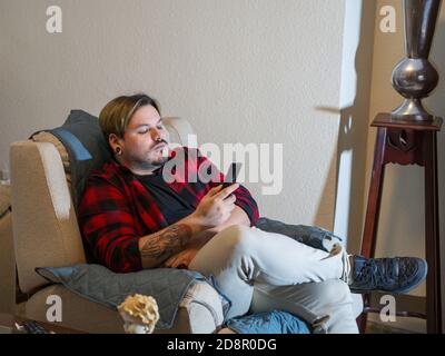 Caucasian man with tattoos looking at his smartphone Stock Photo