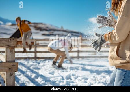 Three girls plays snowballs in mountains. Girl shaking off snow from hands Stock Photo