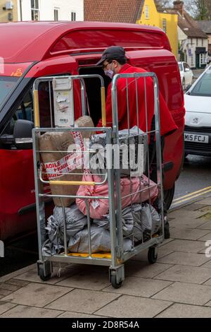 a gpo or royal mail post office van driver postman or delivery and collection driver unloading parcels and letters from a cage into his van. Stock Photo