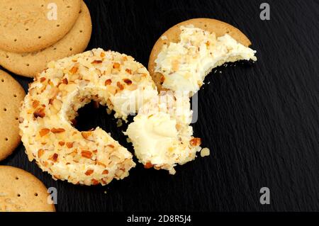 Pineapple flavour soft cream cheese ring coated in crushed almonds on a slate stone background Stock Photo