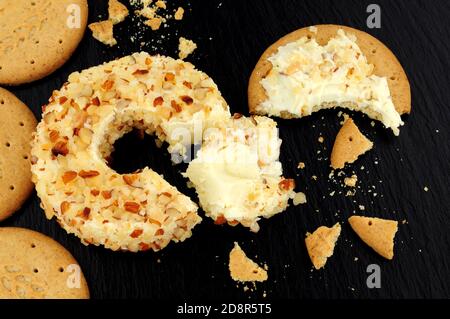 Pineapple flavour soft cream cheese ring coated in crushed almonds on a slate stone background Stock Photo