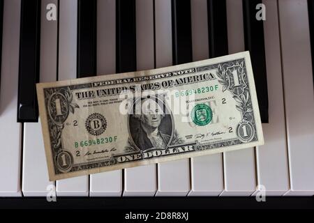 One dollar banknote lying on the piano keys. The dollar as a symbol of global economic management. Stock Photo