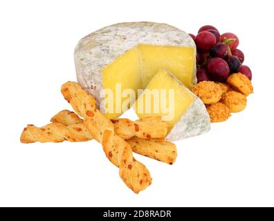 Farmhouse cheddar cheese wheel with red grapes and crispy baked cheese bread twists isolated on a white background Stock Photo