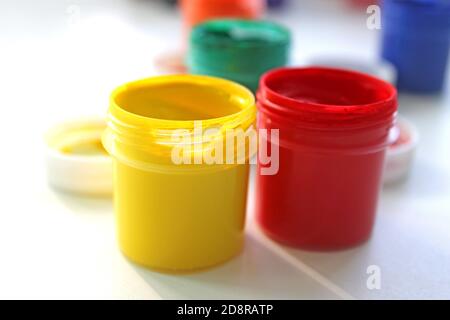 Open gouache jars on white background, flat lay composition,top view.Copy space.Flat lay composition with gouache colors and paintbrushes.advertising Stock Photo