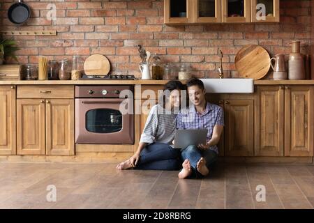 Happy couple relax in cozy kitchen using laptop Stock Photo