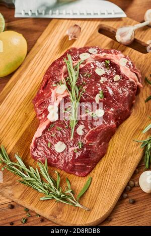 Top view on a raw meat being seasoned with fresh thyme, rosemary and garlic Stock Photo
