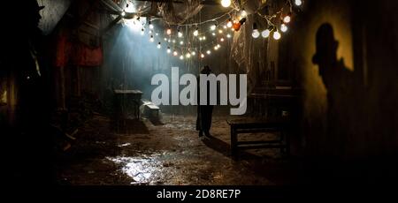 Silhouette of a man in a coat and hat in a dark alley on a rainy night. theme of violence and cruelty Stock Photo