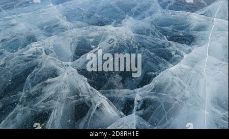 Transparent ice of lake Baikal with a pattern of cracks Stock Photo