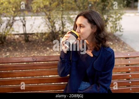 Beautiful woman with dark hair drinking coffee outdoors Stock Photo