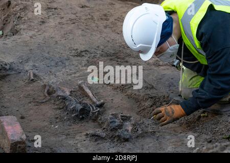 Archeologist working to remove human remains from historic cemetery on Constitution Street in Leith at Edinburgh Tram construction work, Scotland, UK Stock Photo
