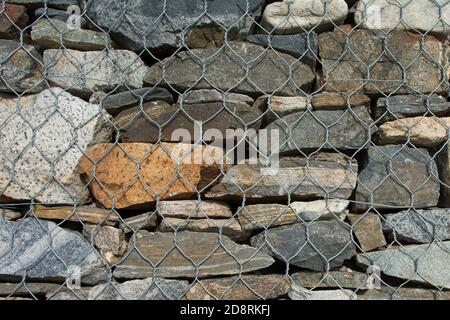 texture background colorful natural stones. Background from natural stones closed with a metal mesh. Stock Photo