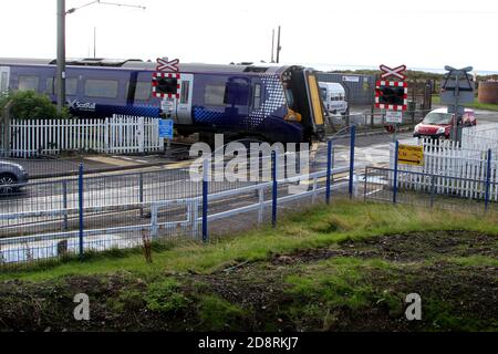 Ardrossan, North Ayrshire, Scotland, UK. A Strathcylde Scotrail passenger train on a level crossing the road at Ardrossan Harbour on a wet day Stock Photo