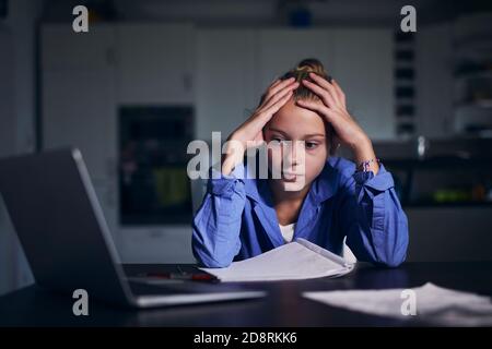 Online school lesson. Schoolgirl learning via internet with laptop at home. Stock Photo