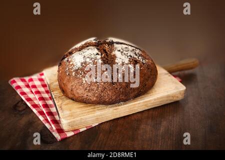 Wholegrain bread on dark ructic wooden background closeup. Round  bread loaf Stock Photo