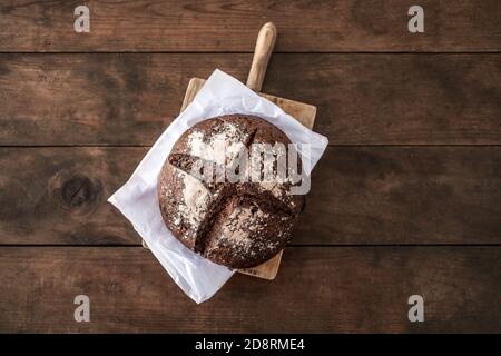 Top view of wholegrain bread on dark ructic wooden background closeup. Round  bread loaf Stock Photo