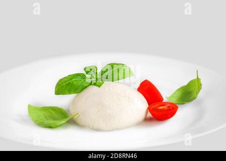 Mozzarella cheese Buffalo on a  plate over white background. Top view. Traditional Italian Mozzarella  with basil leaf and tomatoes close up Stock Photo