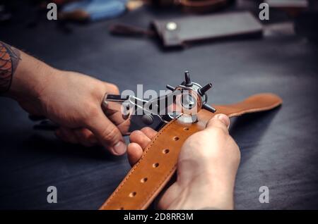 Craftsman performs leather working for a new product in his tanning shop Stock Photo