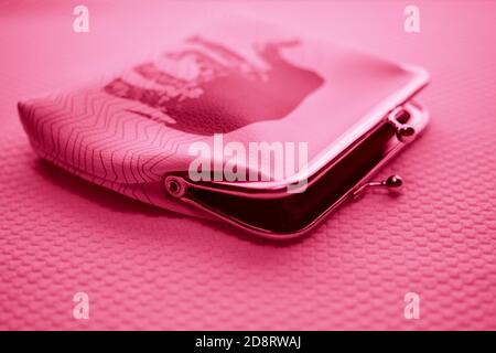 Open purse for coins. Wallet for change. Leather purse closeup on a table. Pink light. Stock Photo