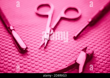 Set of professional manicure tools on table in pink light. Stock Photo