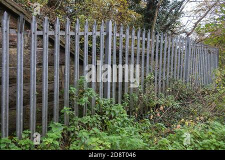 Galvanised steel palisade spiked security fencing on railway banks Stock Photo