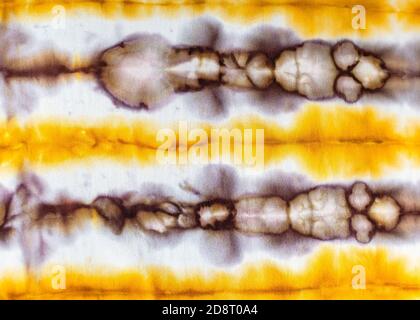 textile background - abstract spotted yellow and brown pattern in tie-dye batik technique on white silk fabric of handcrafted scarf Stock Photo