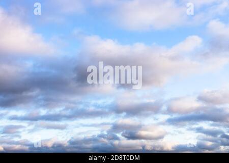 low fluffy gray and white clouds in blue sky in autumn twilight Stock Photo
