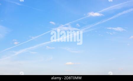 low contrail and little cumuli clouds in blue sky on autumn day Stock Photo