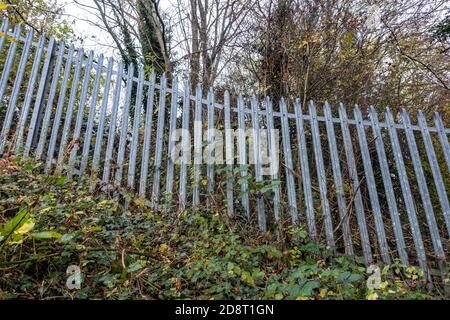 Galvanised steel palisade spiked security fencing on railway banks Stock Photo