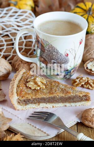 piece of walnut tart and cup of coffee on wooden board Stock Photo