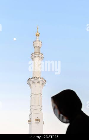 Silhouette of muslim arabic woman, covered in black abaya in front of spile top of white Grand mosque, Abu Dhabi, UAE, evening magrib pray time Stock Photo