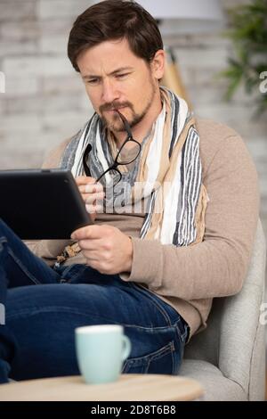 man reading an ebook sitting on a comfortable couch Stock Photo