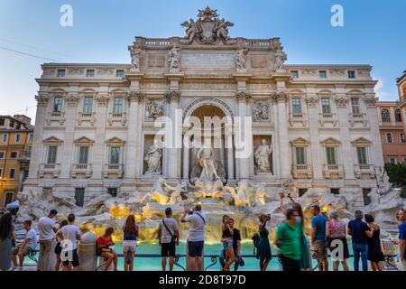 City of Rome, Italy, Trevi Fountain (Fontana di Trevi) at dusk and group of people, tourists enjoy the view of world famous landmark