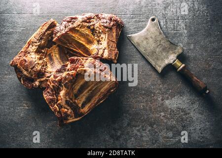 Top view of smoked ribs on a dark metallic surface next to a vintage knife Stock Photo