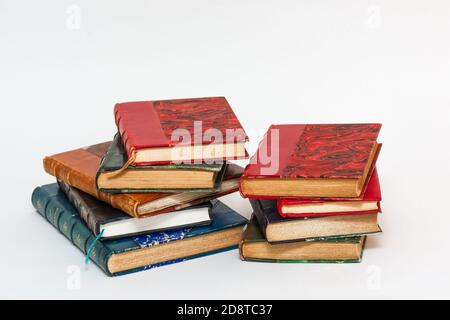 Two stacks of old books with ancient bindings on a white background Stock Photo
