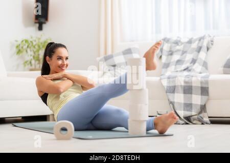 Improvising abs home workout by stacking toilet papers and by reaching feet into their height. Stock Photo