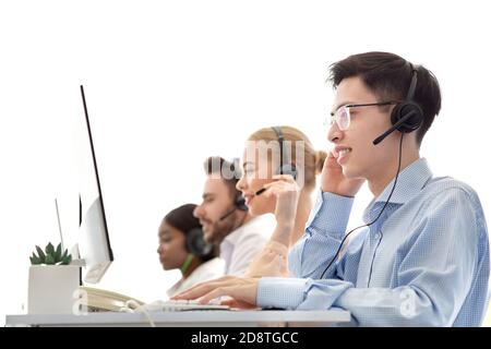 Diverse team of call centre operators working with computers at modern open space office Stock Photo