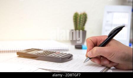 The student solves mathematical formulas. Man writes with a pen in a notebook. Homework. Notes in a notebook. Stock Photo