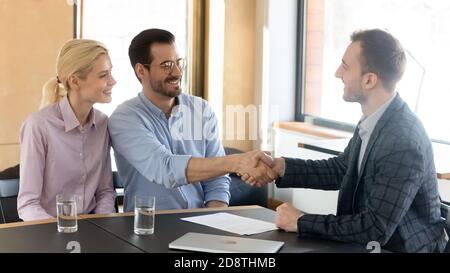 Smiling male financial advisor shaking hands with clients. Stock Photo