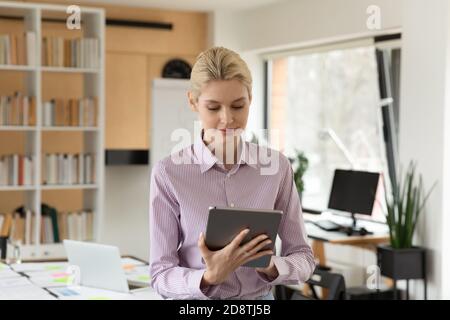 Pleasant smiling young businesswoman using computer tablet. Stock Photo